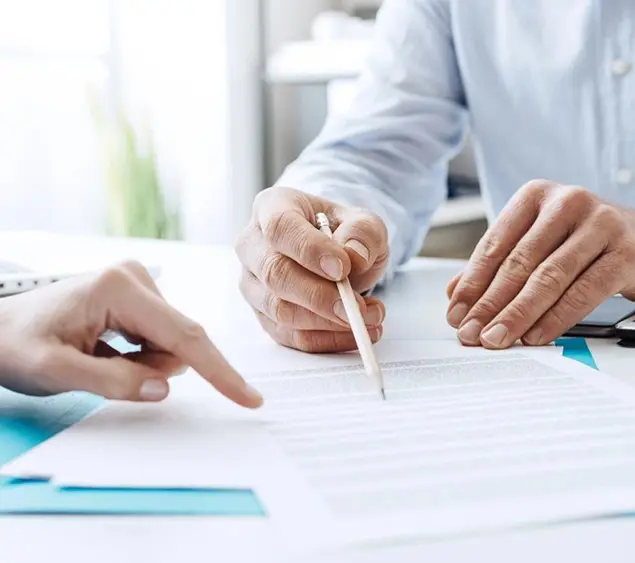 Two people are sitting at a table and one is holding a pencil